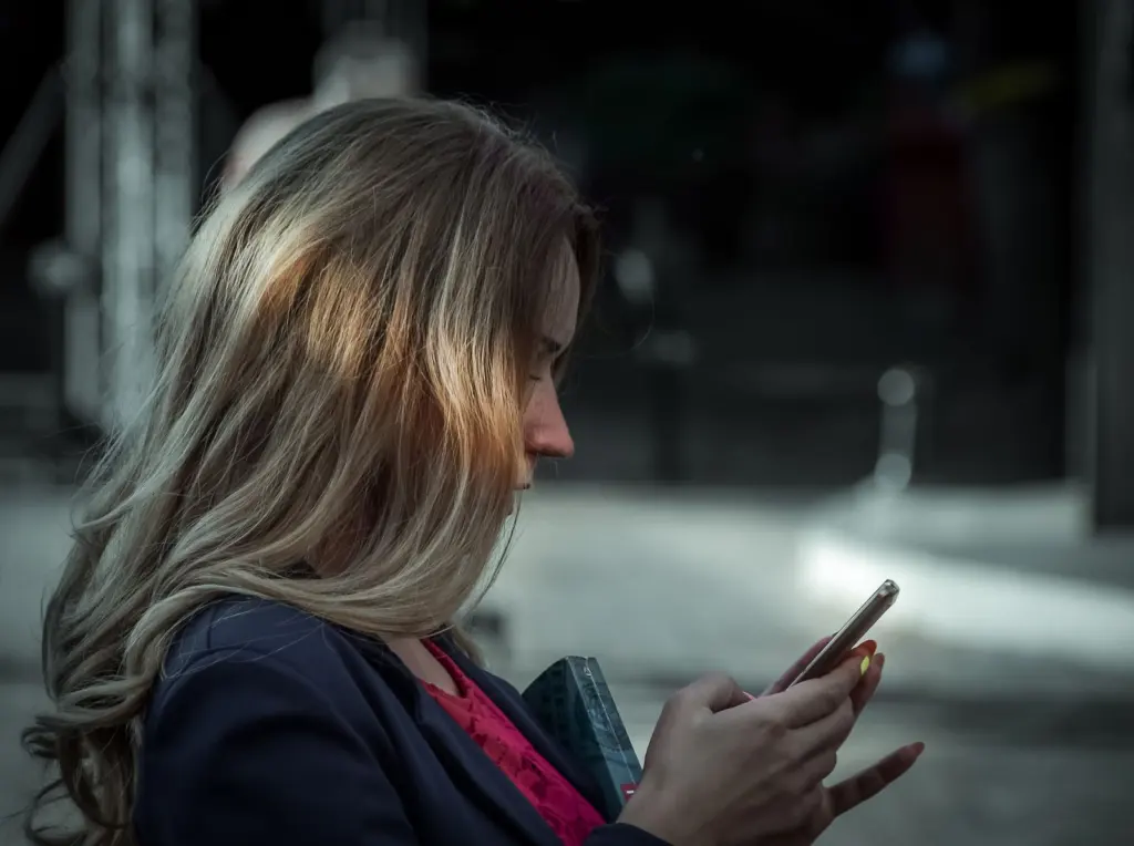 Woman using her phone, the moment a link in bio landing page for coaches needs to convert
